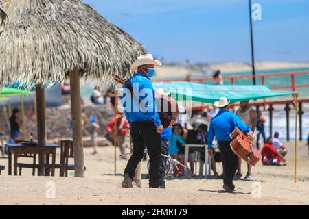 Musiker oder nördliches Popmusik-Ensemble laufen auf dem Sand in einer Palapa-Gegend und legen am Strand oder an der Kino Bay an. Hermosillo, Sonora, Mexiko. Altes Kino. Touristisches Ziel, (Foto von Luis Gutierrez / Norte Photo) Musicos o conjunto de musica popular norteña camina por la Arena en area de palapa y muelle de la playa o Bahía de Kino . Hermosillo, Sonora, Mexiko. Kino viejo. Destino Turistico, (Foto von Luis Gutierrez / Norte Photo) Stockfoto