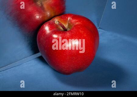 Verspiegelter roter köstlicher Apfel auf blauem Hintergrund Stockfoto