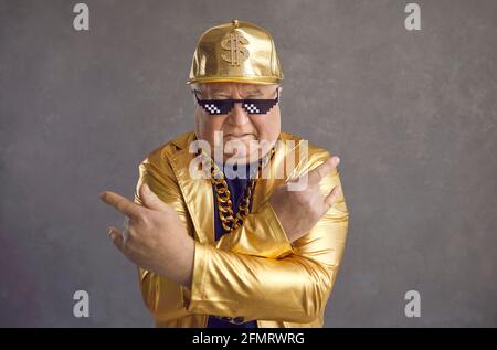 Studioportrait eines coolen älteren Mannes in einer Strolch Life Sonnenbrille Und goldenes Party-Outfit Stockfoto