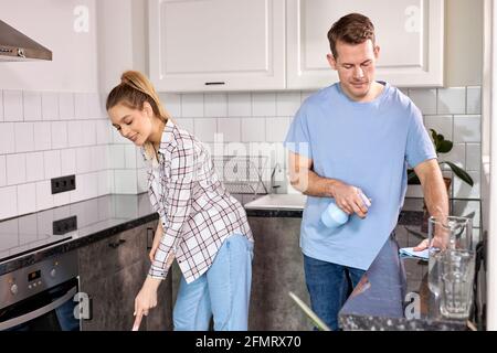 Zwei Janitors Reinigung Küche Und Wischboden Zu Hause, Kaukasischen Mann Und Frau In Casual Weae Genießen Housekeeping, Reinigung Wohnung Wohnung Stockfoto