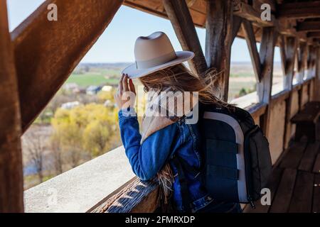 Touristenfrau, die auf dem Balkon des Schlosses Olesko spazieren geht und den Ausblick auf die Frühlingslandschaft bewundert. Reisen in der Westukraine. Stockfoto