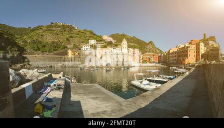 Vernazza, Ligurien, Italien. Juni 2020. Der Hafen des Küstendorfes. Hier blicken die Häuser der farbigen Fassaden. Festfahrte Boote. Ein Junge hat einen coron Stockfoto