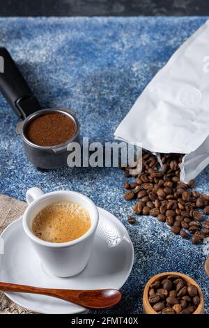 Eine Tasse Kaffee, ein Kaffeebehälter und ein Stapel Kaffeebohnen auf einem Küchentisch Stockfoto
