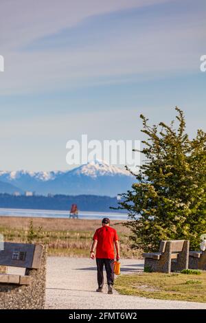 Älterer Mann in einem roten Hemd, der um Garry Point herumläuft Park in Steveston, British Columbia, Kanada Stockfoto