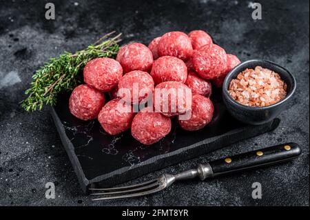 Rohe Fleischbällchen aus Hackfleisch und Schweinefleisch mit Thymian. Holzhintergrund. Draufsicht Stockfoto
