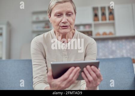 Ältere Frau, die zu Hause ein digitales Tablet verwendet. Der Einsatz von Technologie durch ältere Menschen. Stockfoto