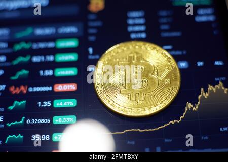 Die Goldbitcoin-Münze liegt auf dem Tablet-Bildschirm, der Cha zeigt Stockfoto