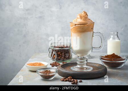 Dalgona-Kaffee und Zutaten auf grauem Hintergrund. Kaffee und Milchgetränk mit Schlagschaum. Stockfoto
