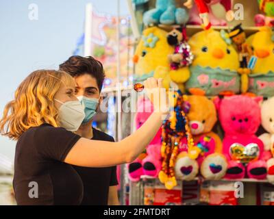 Paar in Masken spielen Pop-Ballons mit Darts Spiel Stockfoto