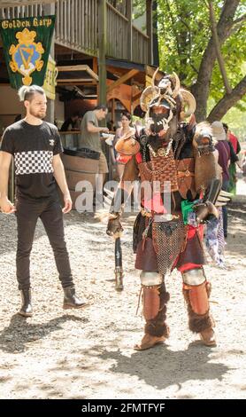 Mann im Ganzkörper-Barbaren-Kostüm komplett mit gehörntem Helm, Ketten aus Leder und Fell, umgeben von anderen Touristen beim Oklahoma Renaissance Festival Stockfoto