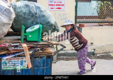 Vietnamesische Frau, die schweren Wagen voller Müll/Recycling schiebt, Hoi an, Vietnam Stockfoto