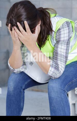 Müde Baumeisterin zieht ihren Helm aus Stockfoto