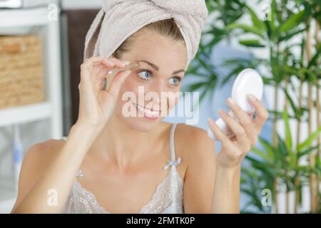 Junge Frau pflückt Augenbraue mit einer Pinzette Stockfoto