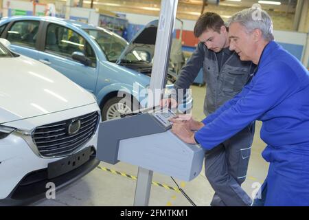 Schüler mit Lehrer, die Reparatur eines Autos während der Lehrzeit Stockfoto