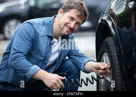Fahrer prüft Luftdruck und Einfüllluft Stockfoto