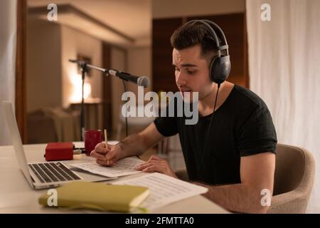 Männlicher Komponist, der Musik hört und Notizen macht Stockfoto