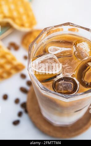 Erfrischender, eisgekühlter Latte-Kaffee in einem Glas mit Herzwaffeln Und Kaffeebohnen Stockfoto