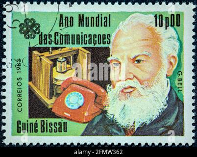 GUINEA - BISSAU - UM 1983: Eine in Guinea-Bissau gedruckte Briefmarke, die dem Weltkommunikationsjahr gewidmet ist, zeigt einen in Schottland geborenen Wissenschaftler-Erfinder eng Stockfoto
