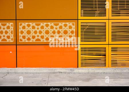 Ein Gebäude aus WC und es ist mit gelben und orangefarbenen Mustern und auch gelben Türen bedeckt. Es ist auf Kopfsteinpflasterstraße. Stockfoto