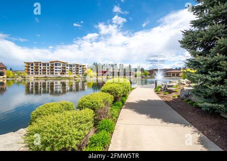 Riverstone öffentlicher Park in Coeur d'Alene, Idaho, USA, mit Restaurants, Neubau und dem Wasserbrunnen, der in den kleinen See sprüht. Stockfoto