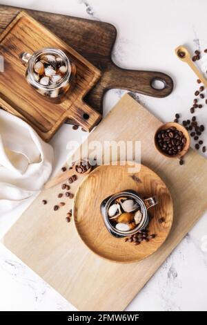 Mason Gläser mit leckeren kalten Brühe und Kaffeebohnen auf Heller Holzhintergrund Stockfoto