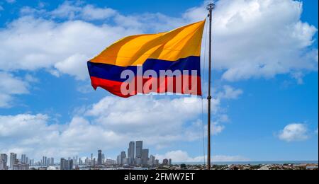 Die Flagge schwankt vor dem malerischen Blick auf die moderne Skyline von Cartagena in der Nähe des historischen Stadtzentrums und der Hotelzone des Resorts. Stockfoto