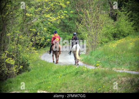 Junges Paar, das auf einer Landstraße auf einem Pferd reitet Hügel Stockfoto