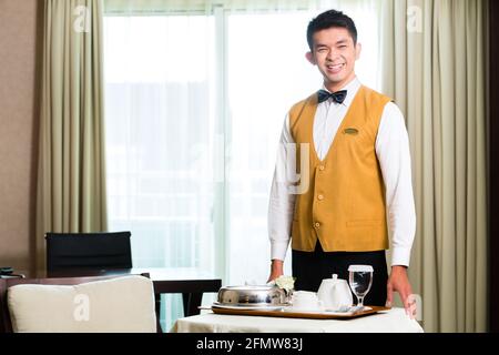 Asiatische chinesische Zimmerservice Kellner oder Steward Gäste Speisen in einem Grand oder Luxus-Hotel-Zimmer Stockfoto