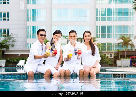 Asiatischen Freunden sitzen von den Hotel Swimmingpool mit Cocktails Stockfoto