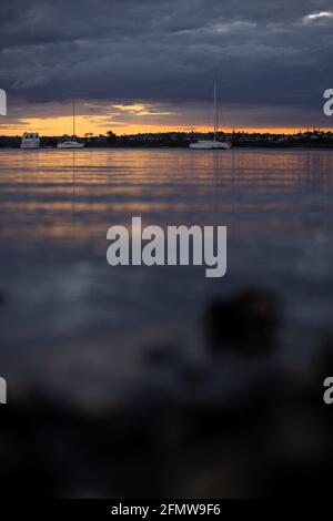 Sanfte Wellen, die aus einem niedrigen Winkel am Ufer des Waitemata Harbour mit festgetäuten Yachten in Sunset, Neuseeland, schwappen Stockfoto