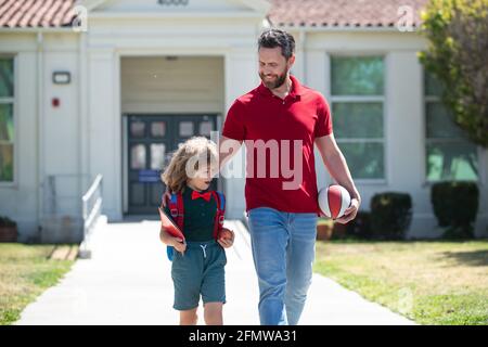 Vater unterstützt und motiviert Sohn. Kind geht zur Grundschule. Lehrertag. Stockfoto