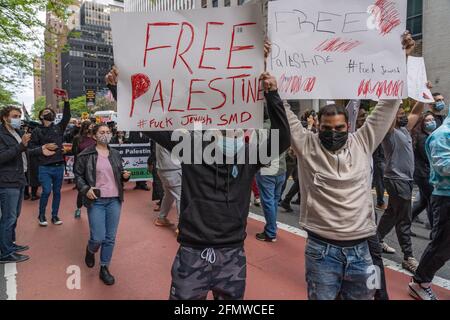 NEW YORK, NY - 11. MAI: Pro-palästinensische Anhänger halten während eines marsches auf der 42. Straße in Manhattan am 11. Mai 2021 in New York City Zeichen ab. Die Feindseligkeiten zwischen Israel und der Hamas eskalierten über Nacht, wobei 35 Palästinenser in Gaza und 5 in Israel während des intensivsten Luftaustauschs seit Jahren getötet wurden. Zentralisrael wurde von einer massiven Raketenabschusswelle aus dem Gazastreifen getroffen, kurz nachdem die Hamas vor einem Sperrfeuer auf das Gebiet von Tel Aviv gewarnt hatte, falls die IDF die Luftangriffe auf zivile Gebäude im Gazastreifen nicht einstellte. Nach Angaben der IDF wurden innerhalb von 18 Stunden 300 Raketen aus dem Gazastreifen abgefeuert. Ha Stockfoto