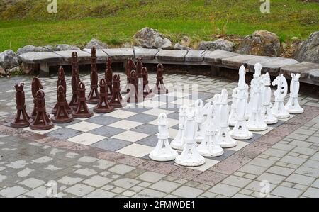 Große Schachfiguren aus Holz an Bord draußen Stockfoto