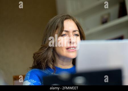 Frau, die vor sich lacht, als sie Medien über sie liest Laptop-Computer in einer Nahaufnahme aus dem niedrigen Winkel mit Fokussiere dich auf ihr Gesicht Stockfoto