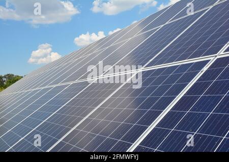 Nahaufnahme eines Solarpanels mit zahlreichen Solarmodulen und Photovoltaikzellen vor blauem Himmel mit weißen Wolken als Quelle alternativer Energie. Stockfoto