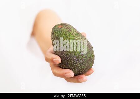 Hand mit einer frischen und reifen Avocado: Selektiver Fokus und Nahaufnahme. Frisches und gesundes Lebensmittelkonzept Stockfoto