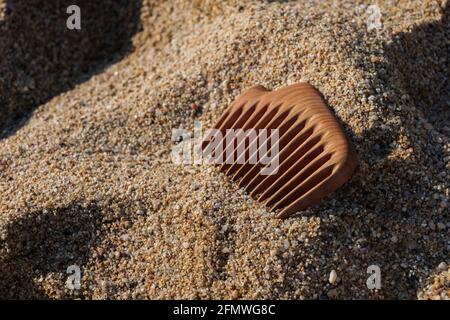 Handgefertigter Holzkamm auf Sand am Strand. Wird für Kopfmassage und Kämmen verwendet. Haarpflegekonzept. Stockfoto