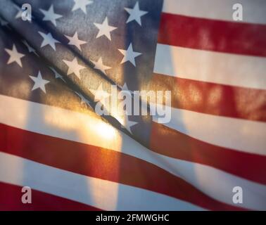 Sonnenlicht, das am Morgen durch eine amerikanische Flagge scheint. Nahaufnahme. Stockfoto