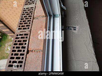 Kunststoff-Fensterinstallation: Nahaufnahme eines uPVC-Fensterrahmens ohne Glaspaneele in einem neuen Backsteinhaus. Stockfoto