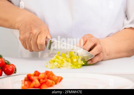 Hände schneiden frischen Salat mit einem Messer auf einem Schnitt Platine Stockfoto