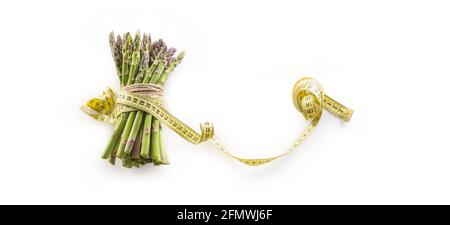 Frischer grüner Spargel mit Maßband isoliert auf weißem Hintergrund. Stockfoto