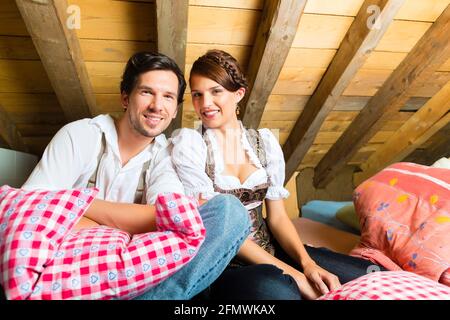 Junges Paar im Bett auf dem Boden einer Scheune oder einer Berghütte in den Alpen, die Freizeit genießen Stockfoto