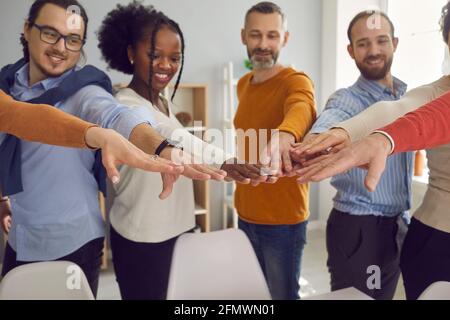 Ein glückliches Lächeln auf den Lippen: Die verschiedenen Mitglieder des Geschäftsteams treffen ihre Hände nach dem anderen Firmenmeeting Stockfoto