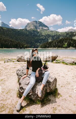 Frau entspannen in den Bergen und hält niedlichen Hund Stockfoto