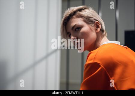 Porträt eines Gefangenen in oranger Uniform gegen die Hintergrund der Gefängnisbars Stockfoto