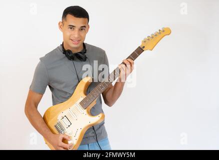 Hübscher junger Mann, der auf weißem Hintergrund isoliert E-Gitarre spielt. Stockfoto