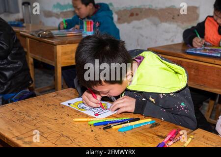 Schüler einer Grundschule im ländlichen China arbeiten an einem Kunst- und Handwerksprojekt. Stockfoto