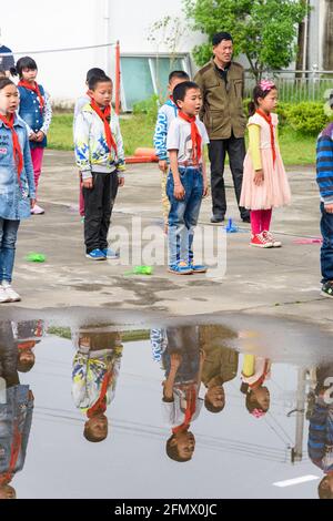 Schüler, die zu Beginn des Schultages an der Flaggenanhebung teilnehmen. Stockfoto