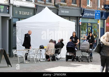 Gloucester, Gloucestershire, Großbritannien - Mittwoch, 12. Mai 2021 - die Polizei setzt ihre Suche im Clean Plate Café im Stadtzentrum fort. Beamte suchen nach Mary Bastholm, die 1968 im Alter von nur 15 Jahren vermisst wurde und möglicherweise Opfer des Serienmörders Fred West wurde. Das Foto zeigt die geschäftige Straßenszene vor dem weißen Polizeizelt um 11.30 Uhr. Foto Steven May / Alamy Live News Stockfoto