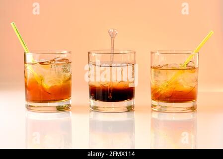 Drei Cocktails auf orangefarbenem Hintergrund, god Mother, Black Russian und god Father im Glas mit Eis Stockfoto